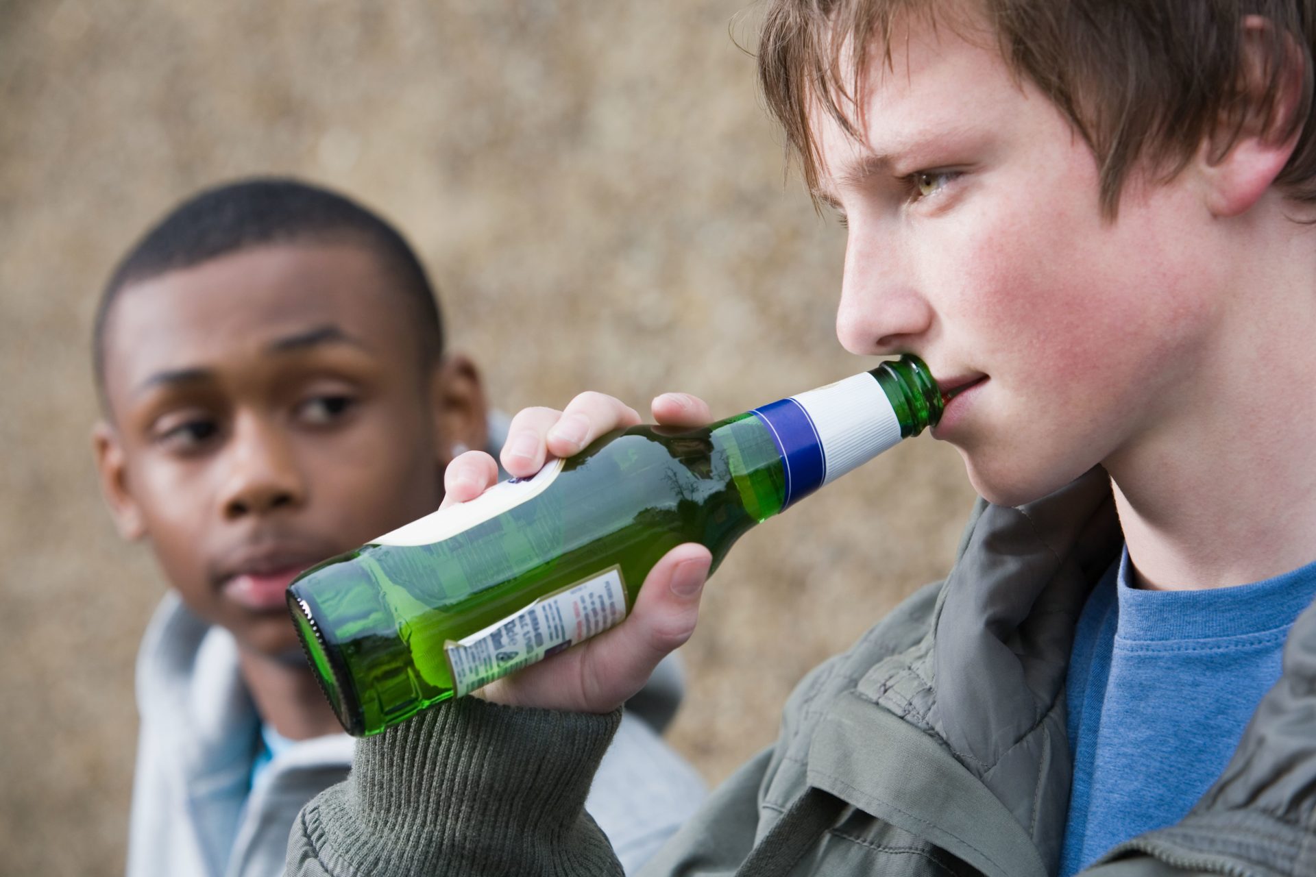 Teenage boy drinking beer with his friend.