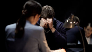Young man covering his face as police interview him.