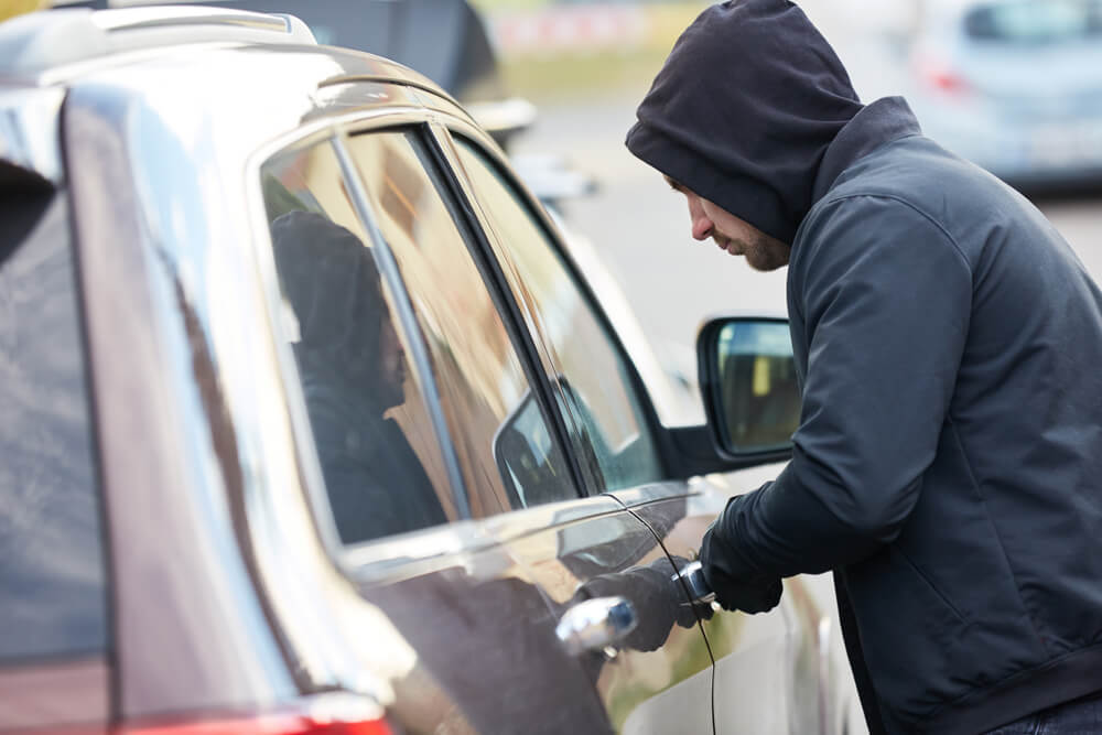 Car thief stealing a car at the car door.