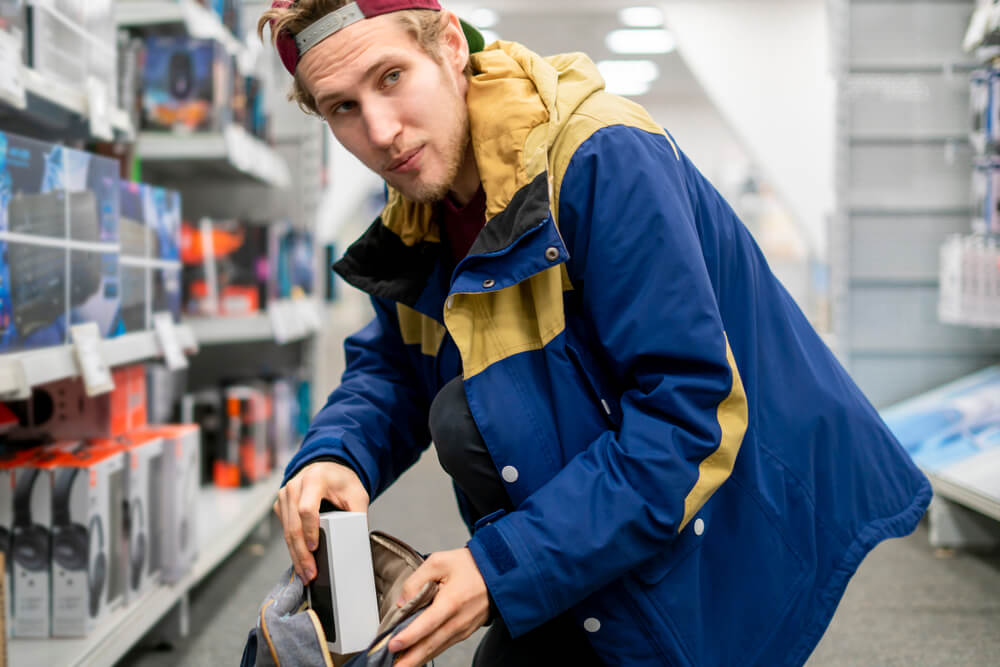 Shoplifter in the electronic store supermarket stealing new gadget.